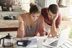 Young Married Couple With Many Debts Doing Paperwork Together Reviewing Their Bills Planning Family Budget Calculating Finances Kitchen Table With Papers 273609 1653