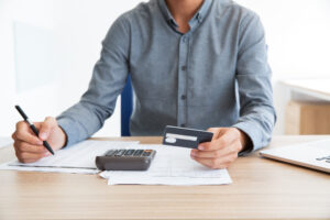 Man Writing Credit Card Number At Desk